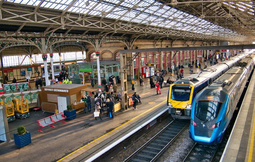 Two trains at platforms in Preston Station in the north west of England in the UK. The architecture of the roof is visible.