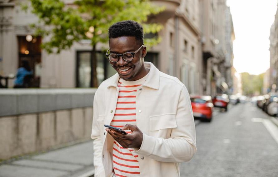  The portrait of an African-American man is on the street, he is walking and using a mobile phone on the go