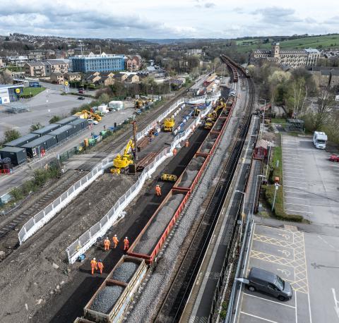 Aerial view of railway track works, workers and diggers.